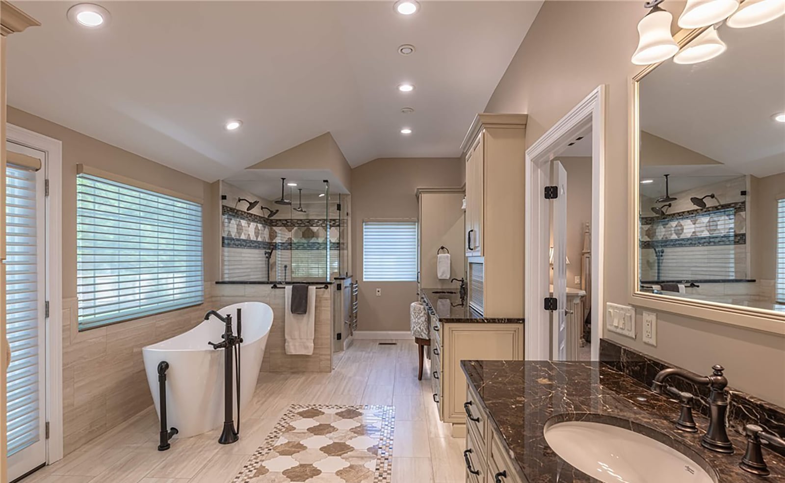 The primary ensuite bathroom has custom tile flooring, a freestanding bathtub, two vanities and a custom tiled walk in shower with programmable fixtures. There are two walk in closets.