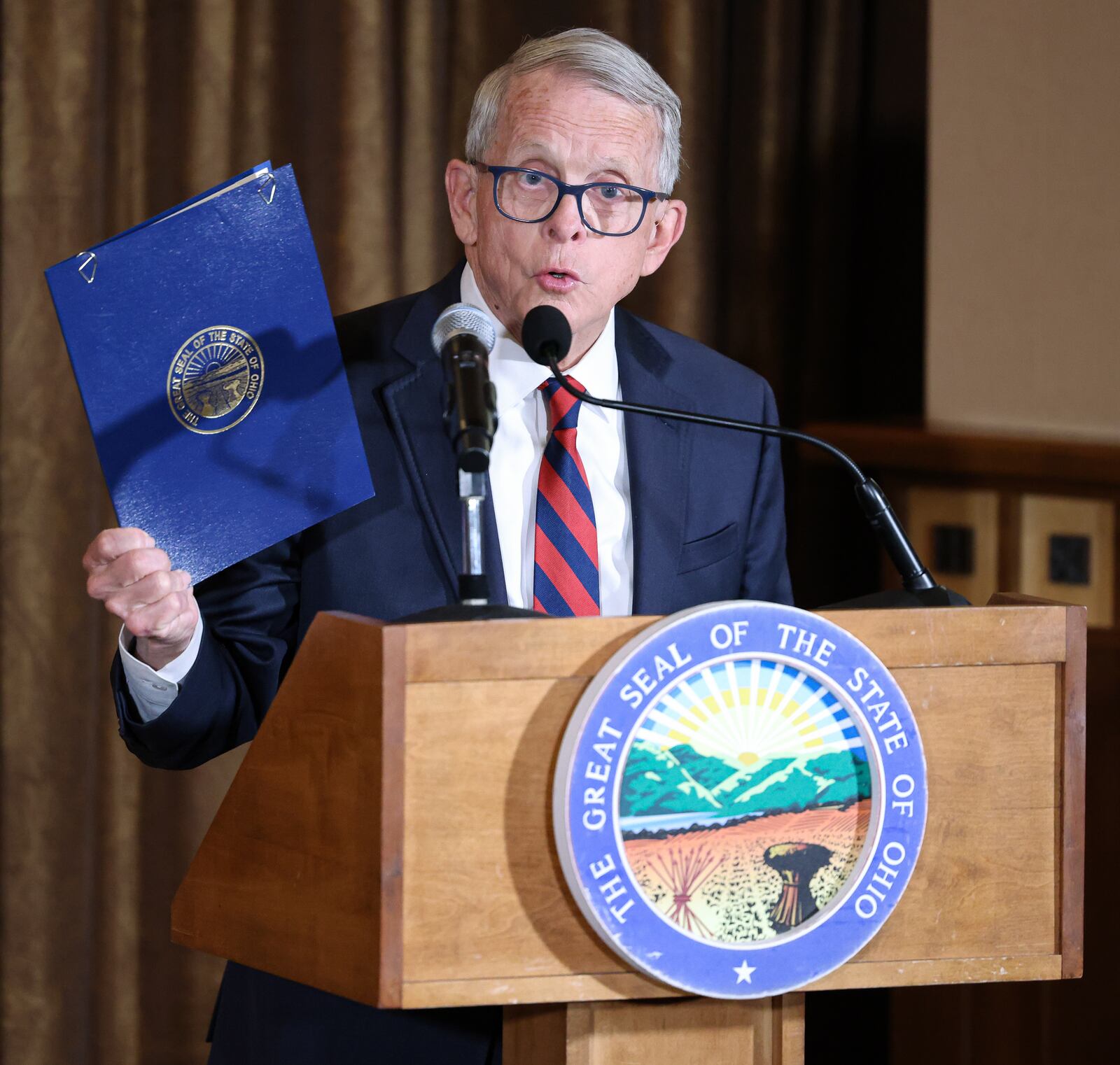 Gov. Mike DeWine speaks while holding up a memorandum of understanding between the State of Ohio and Air Force Research Laboratory to renew a partnership between the entities to share science and technology information and foster economic development within the state. DeWine signed the memorandum during a ceremony on Monday at Pentagon Tower in Beavercreek. BRYANT BILLING / STAFF