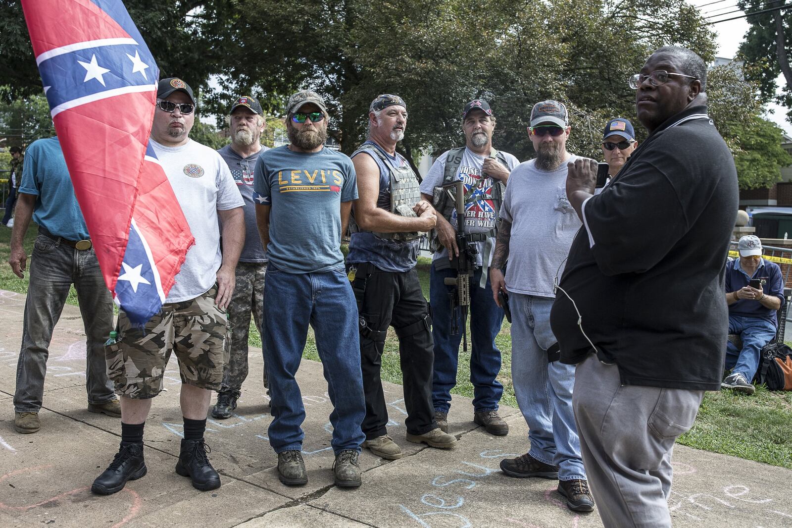 A man with an assault rifle and another with a Confederate flag among a group in Charlottesville, Va., the scene of violent clashes between white nationalists and counterprotesters, Aug. 12, 2017. After the “Unite the Right” rally descended into violence and was subsequently dispersed, a car plowed into a crowd of counterprotesters, killing at least one person and injuring at least 19 others. (Edu Bayer/The New York Times)