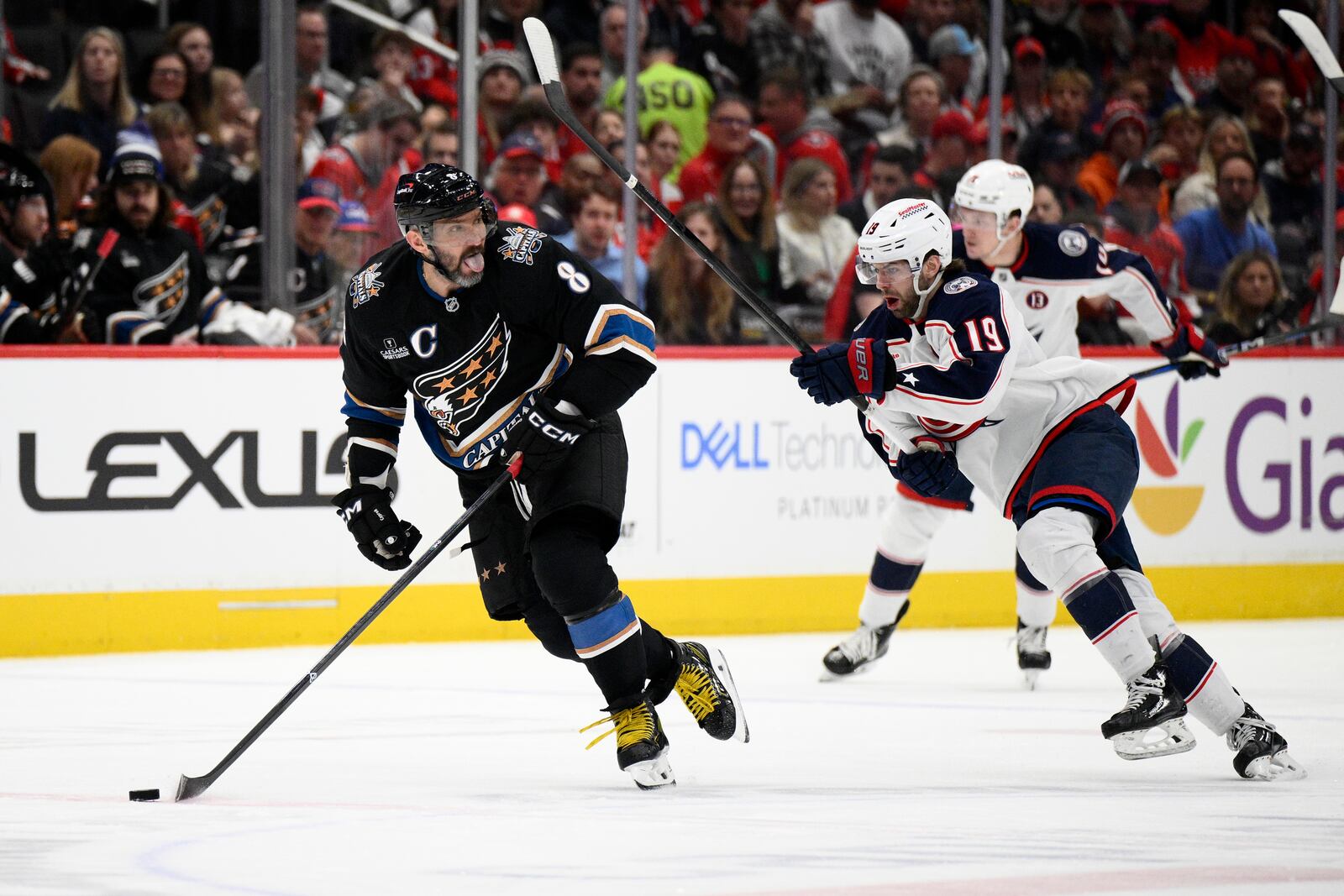 Washington Capitals left wing Alex Ovechkin (8) skates with the puck past Columbus Blue Jackets center Adam Fantilli (19) during the first period of an NHL hockey game, Sunday, April 13, 2025, in Washington. (AP Photo/Nick Wass)