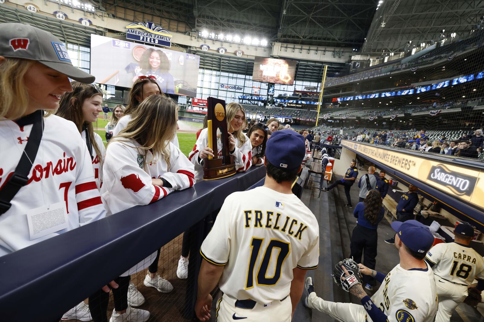 Members of the Wisconsin Badgers NCAA championship woman's hockey team talk to Milwaukee Brewers' Sal Frelick (10) before the first inning of a baseball game between the Cincinnati Reds and Milwaukee Brewers, Thursday, April 3, 2025, in Milwaukee. (AP Photo/Jeffrey Phelps)