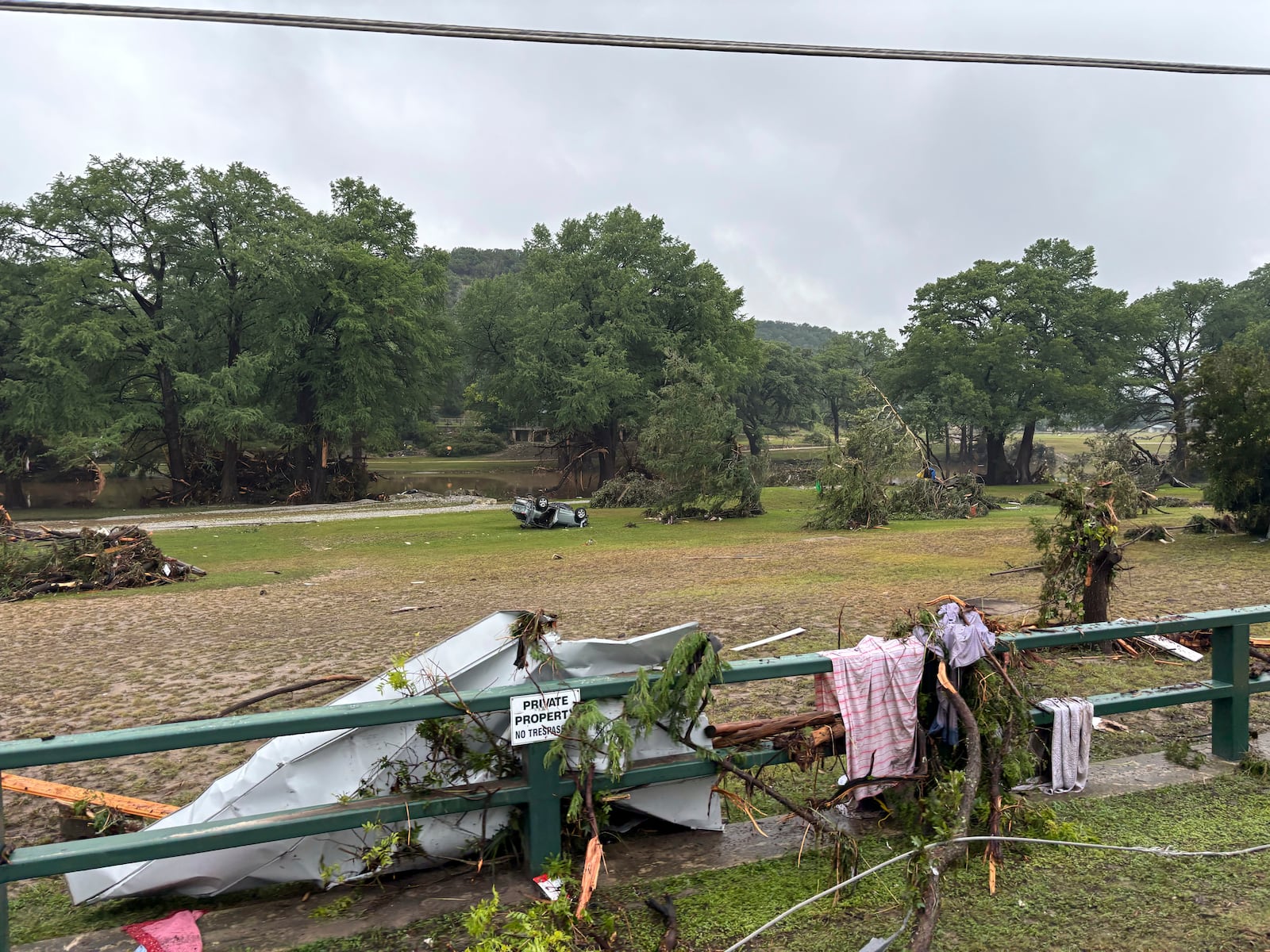 Residents drive past debris as they are transported to a shelter from Hunt, Texas, at 6:34 p.m. on Friday, July 4, 2025, after floodwaters from the Guadalupe River devastated their town. (Shabd Simon-Alexander via AP)
