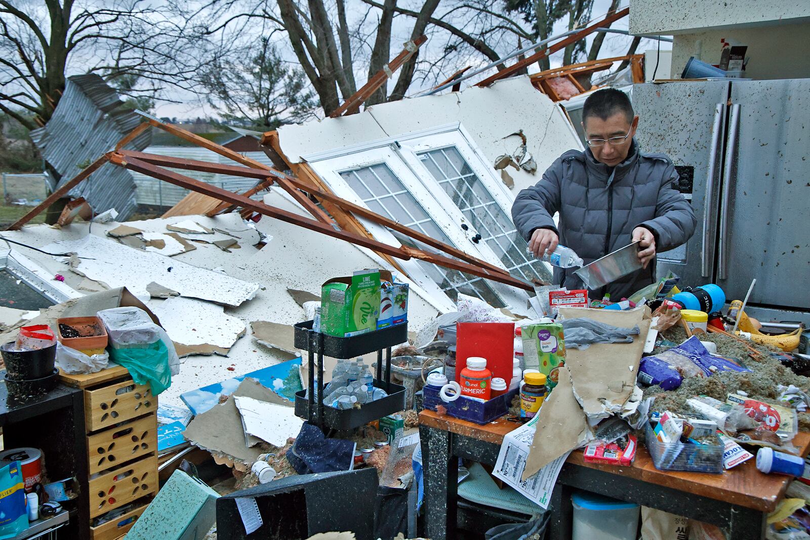 Shoji Uota pours his dog some fresh water after finding the dog's bowl in the debri that's remains of his kitchen after Wednesday's storm destroyed his house on Ridge Road. BILL LACKEY/STAFF