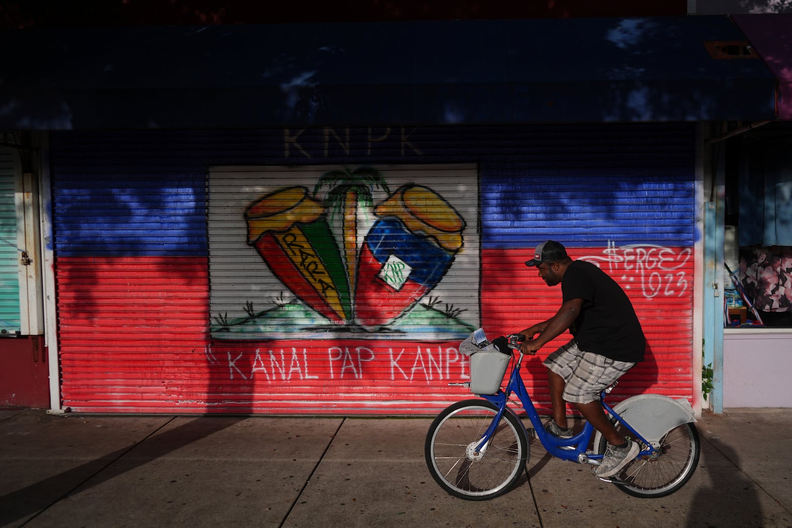 A man rides a bike past shops in Miami's Little Haiti neighborhood, Friday, June 6, 2025. (AP Photo/Rebecca Blackwell)