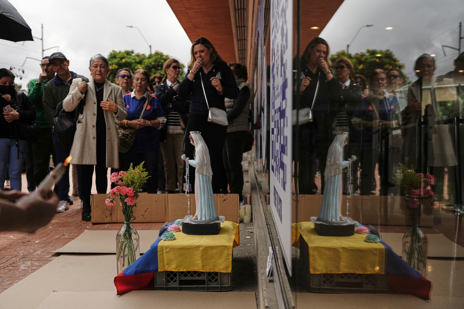 People pray near an altar set up outside the clinic where Colombian Senator Miguel Uribe Turbay is being treated after being shot at a political rally, in Bogota, Colombia, Tuesday, June 10, 2025. (AP Photo/Ivan Valencia)