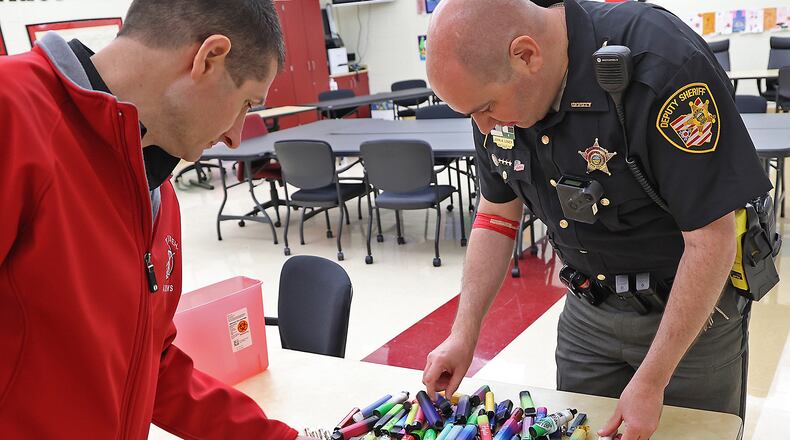 Brian Dixon, director of Safety at Tecumseh Local Schools, and Deputy John Loney, the school's resource officer, look through some of the vape pens that have been confiscated from students in this 2022 image. The Clark County Combined Health District has seen an increase in vaping -- with some as young as fifth grade -- and has developed a five-year strategic plan to bring the numbers down. BILL LACKEY/STAFF