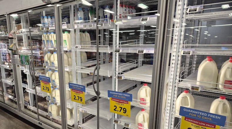 The milk shelves at the Springboro Kroger were empty Thursday and people stocked up before Saturday's forecasted large snow storm. Michael Kurtz / Staff