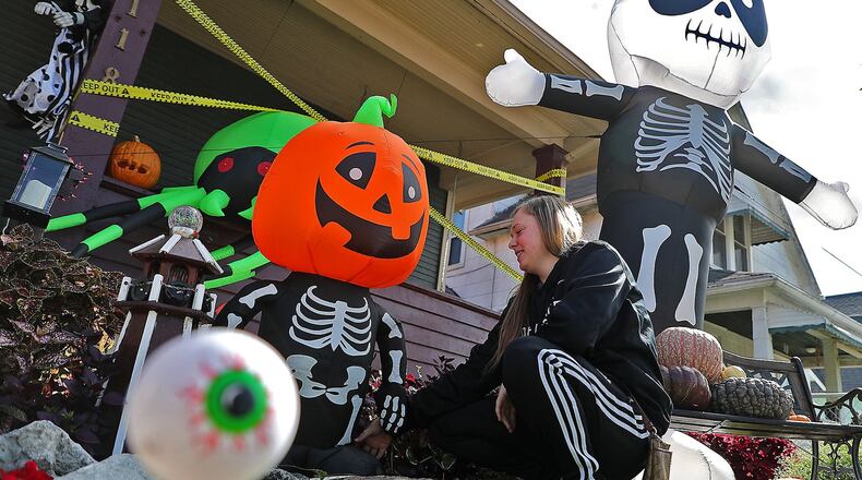 Aria Gohl sets up one of her mother’s Halloween decorations that blew over in the wind Tuesday in their front yard along North Belmont Avenue. BILL LACKEY/STAFF