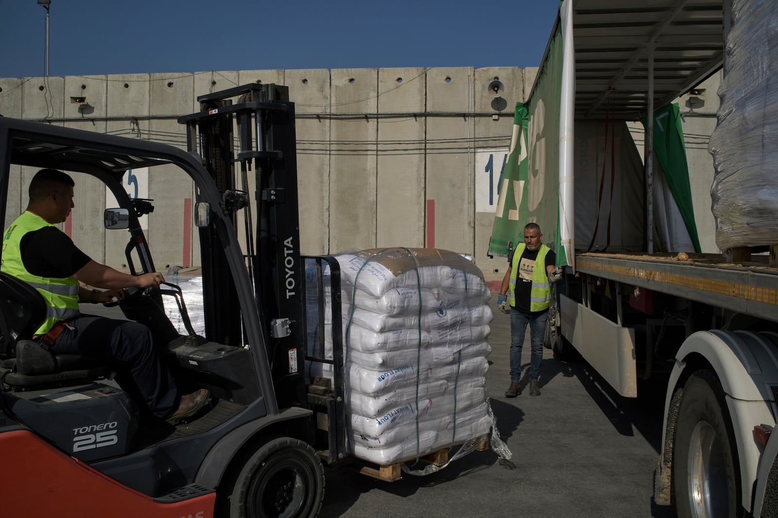 Workers unload cargo from a truck carrying humanitarian aid for the Gaza Strip at the offload area of the Kerem Shalom border crossing between Israel and Gaza, southern Israel, Thursday, May 22, 2025. (AP Photo/Leo Correa)