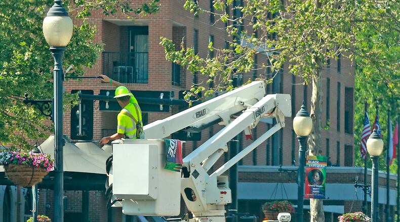 A city of Springfield worker hangs banners for Springfield's Pride Festival on street light poles in downtown Thursday, June 1, 2023. BILL LACKEY/STAFF