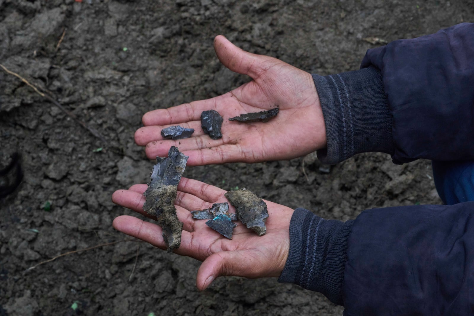Kashmiri villager Mohammad Rafiq displays shrapnel of a shell as he sits near a crater outside his damaged house following overnight shelling from Pakistan at Gingal village in Uri district, Indian controlled Kashmir, Friday, May 9, 2025. (AP Photo/Dar Yasin)