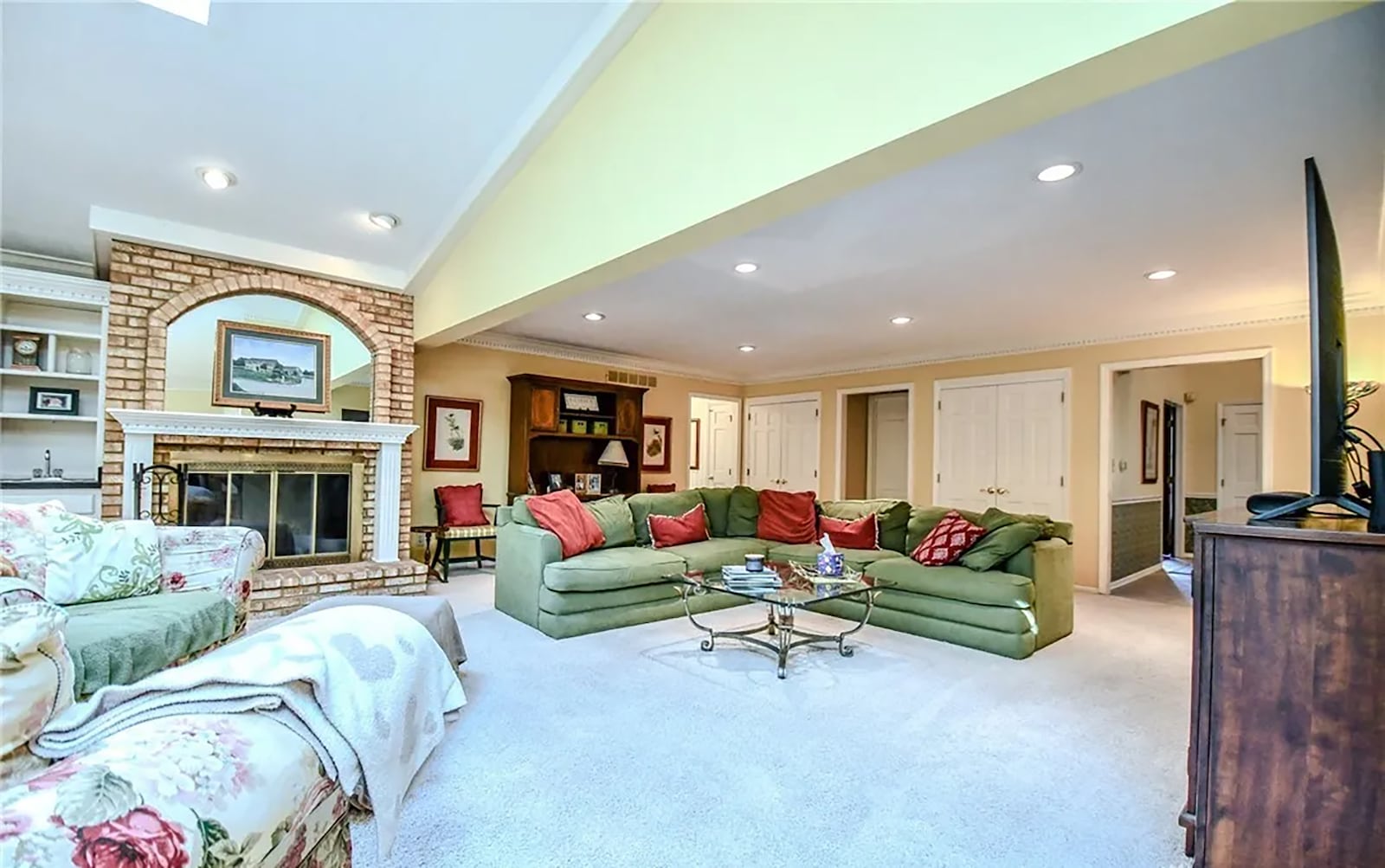 The great room is vaulted with recessed lighting and skylights. It has carpeting and a brick fireplace with glass doors and a raised hearth. CONTRIBUTED