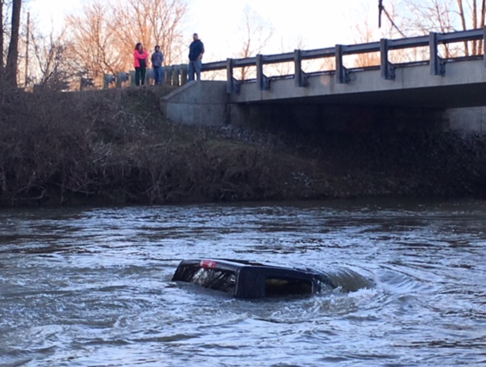 The pickup truck, which has been in the Mad River since Friday, is now mostly in the water on Monday evening, Feb. 26, 2018. (Bill Lackey/Staff)