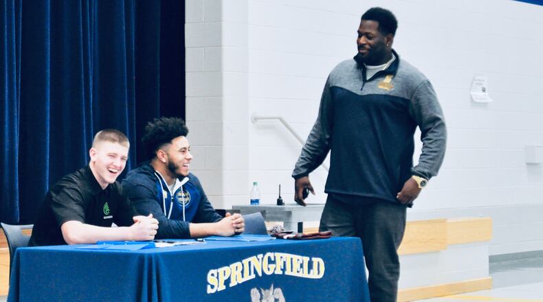 Springfield High School seniors Zack Breslin (let) and Tavion Smith (center) share a laugh with linebackers’ coach C.J. Peake before the start of a signing day ceremony at the school, Feb. 6, 2019. Nick Dudukovich/CONTRIBUTED