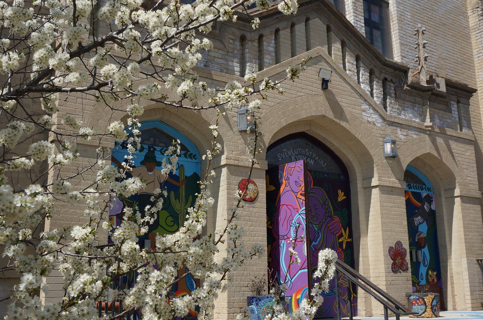 Spring blossoms bloom on a tree next to the entrance of St. Paul’s-San Pablo Lutheran Church, a congregation founded by Swedish immigrants in the late 19th century that has started offering wellness programs in its sanctuary as part of its migrant ministry, in Minneapolis, Sunday, April 27, 2025. (AP Photo/Giovanna Dell’Orto)