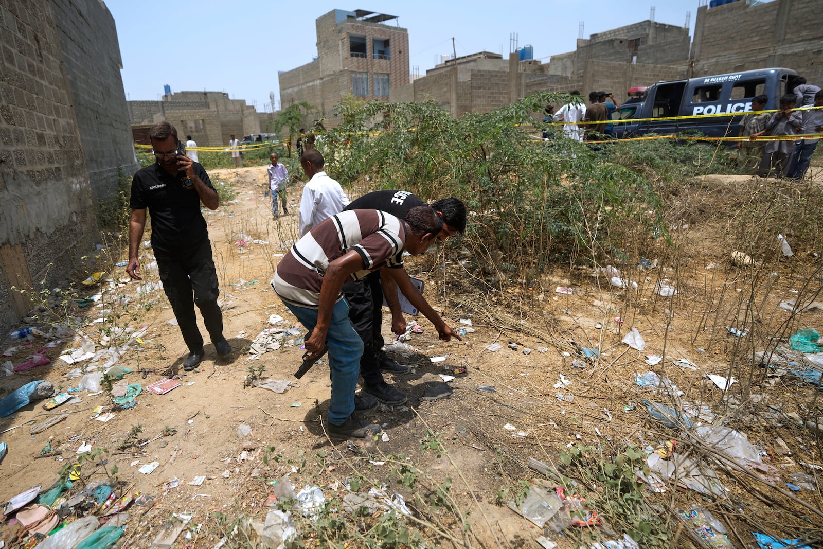 Pakistani investigators examine at a cordoned off site, where Pakistan's air defense system shot down a suspected Indian drone, in Karachi, Pakistan, Thursday, May 8, 2025. (AP Photo/Fareed Khan)