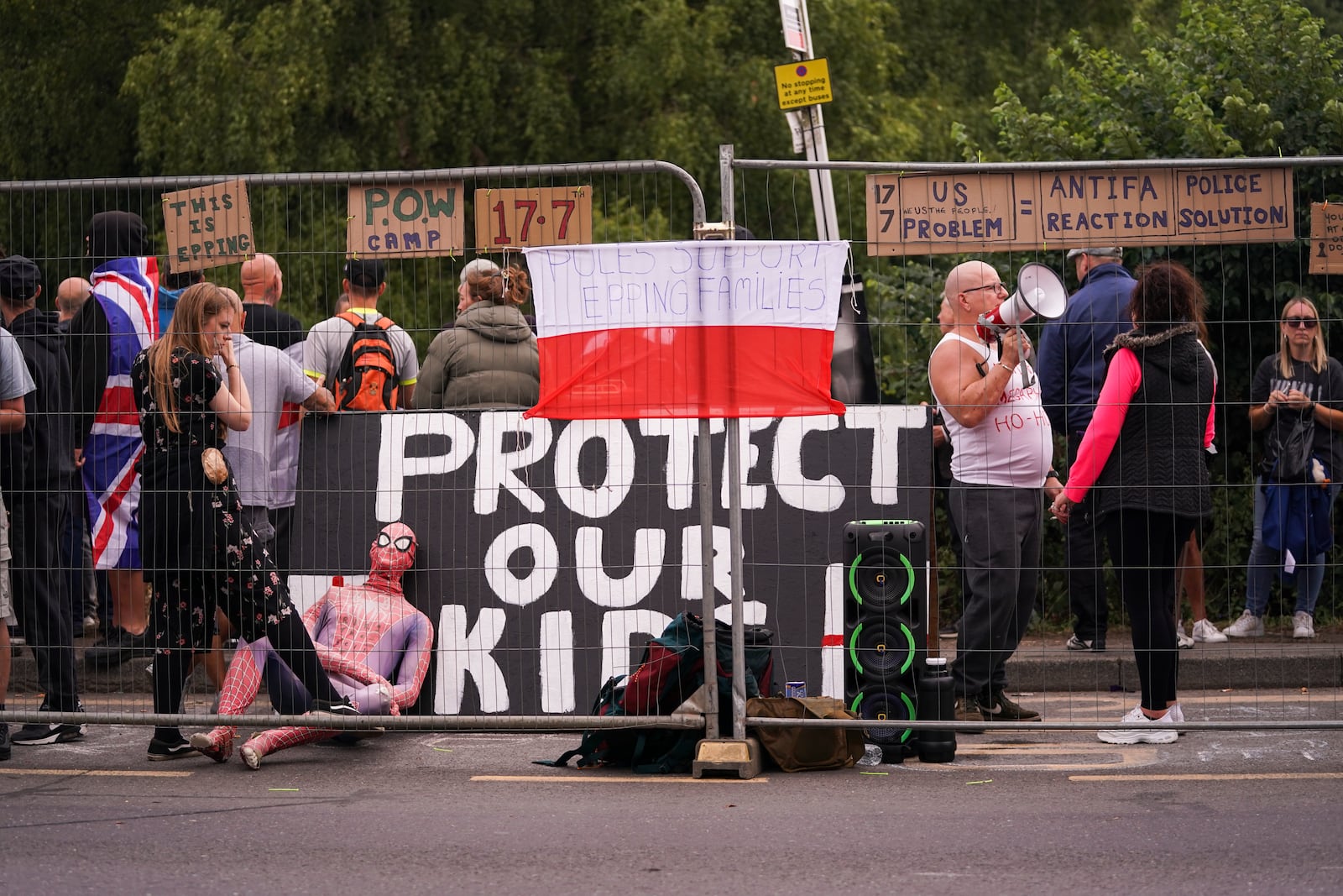 Demonstrators hold flags and placards as they stand outside the Bell Hotel in Epping, near London, Sunday, July 27, 2025.(AP Photo/Alberto Pezzali)