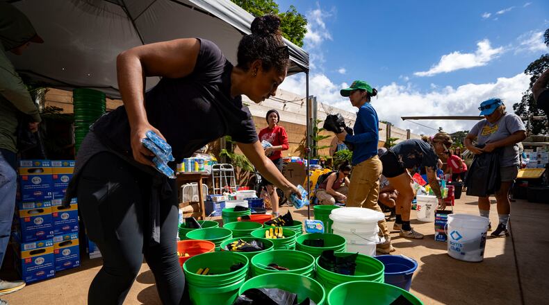 Volunteers sort donated supplies for distribution at Haleiwa Distillery following recent flooding, Tuesday, March 24, 2026, in Waialua, Hawaii. (AP Photo/Mengshin Lin)