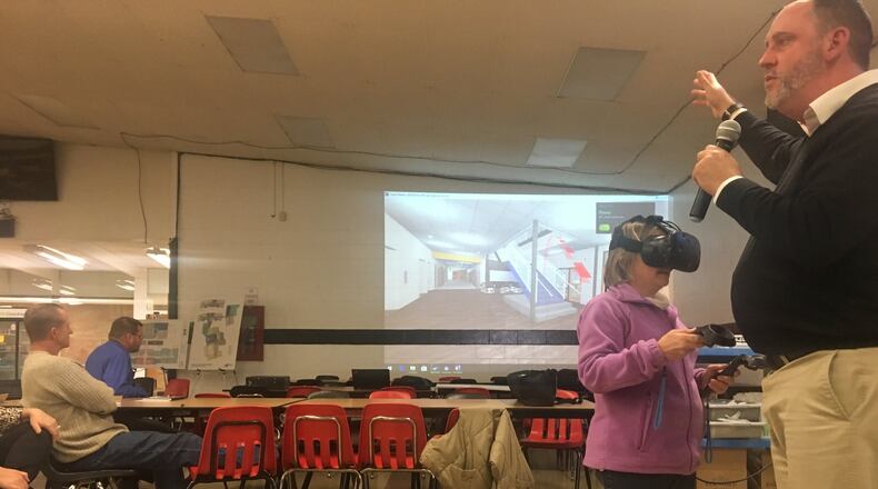 SHP Leading Design Project Manager John Predovich speaks as Greenon resident Sabrina Akers wears virtual reality goggles and takes a tour of a high school.