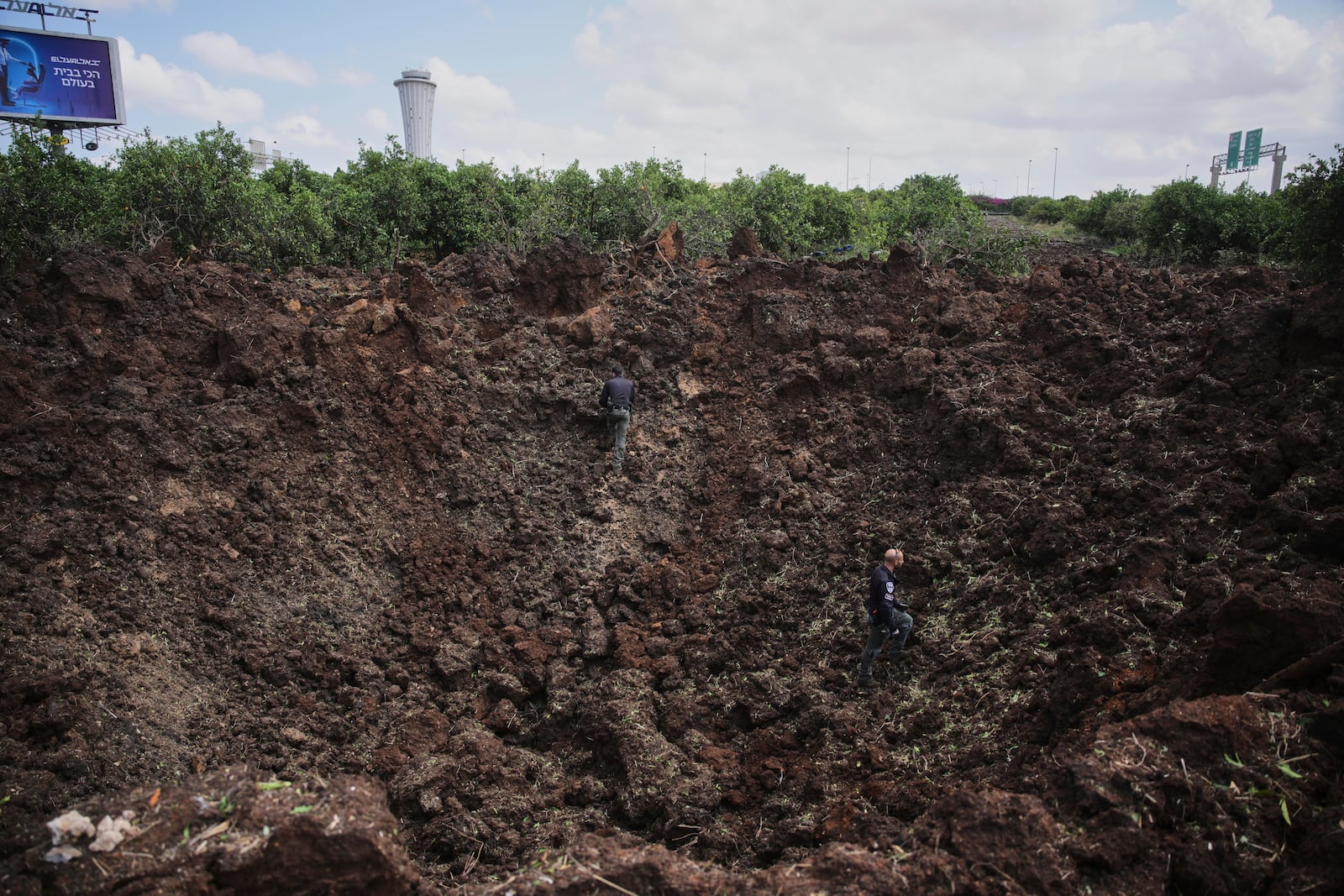 Israeli security forces inspect a crater at the site where the Israeli military said a projectile fired by Yemen's Houthi rebels landed in the area of Ben Gurion International Airport near Tel Aviv, Israel, on Sunday, May 4, 2025. (AP Photo/Ohad Zwigenberg)