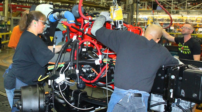 Navistar International employees work on the assembly line putting an engine in a new truck in 2018. JEFF GUERINI/STAFF