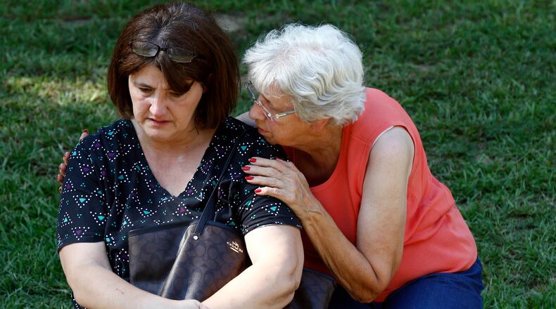 Jonell Payton, right, comforts Lisa Dew, outside the Durant, Miss., home of two slain Catholic nuns, Thursday, Aug. 25, 2016. The nuns worked as nurses at the Lexington Medical Clinic, where Dew was the office manager. Dew and a Durant police officer discovered their bodies inside the house after both nuns did not report for work. (AP Photo/Rogelio V. Solis)
