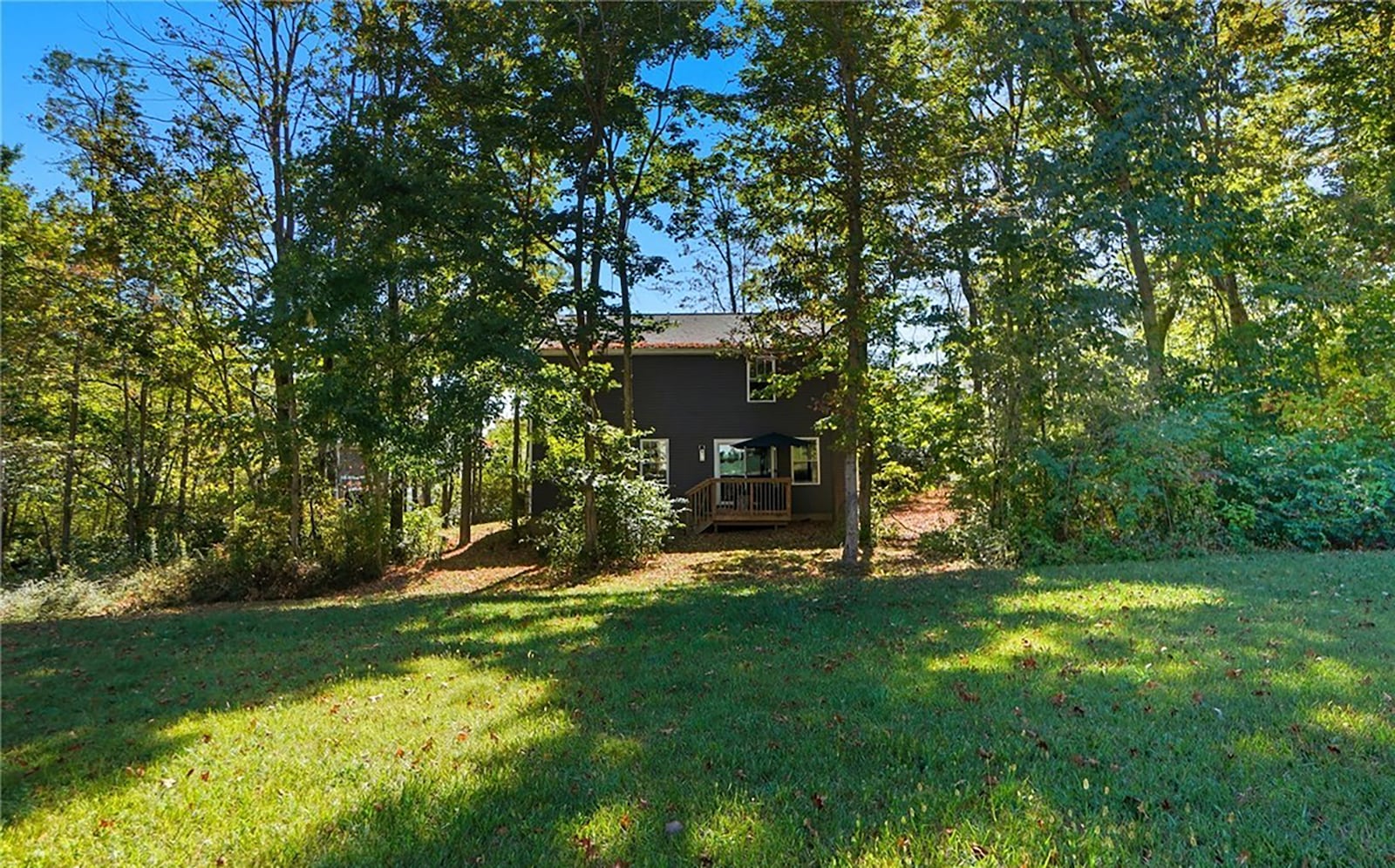 The back of the home has a wood deck with railings and a wooded lot with an outbuilding with a wood deck. CONTRIBUTED