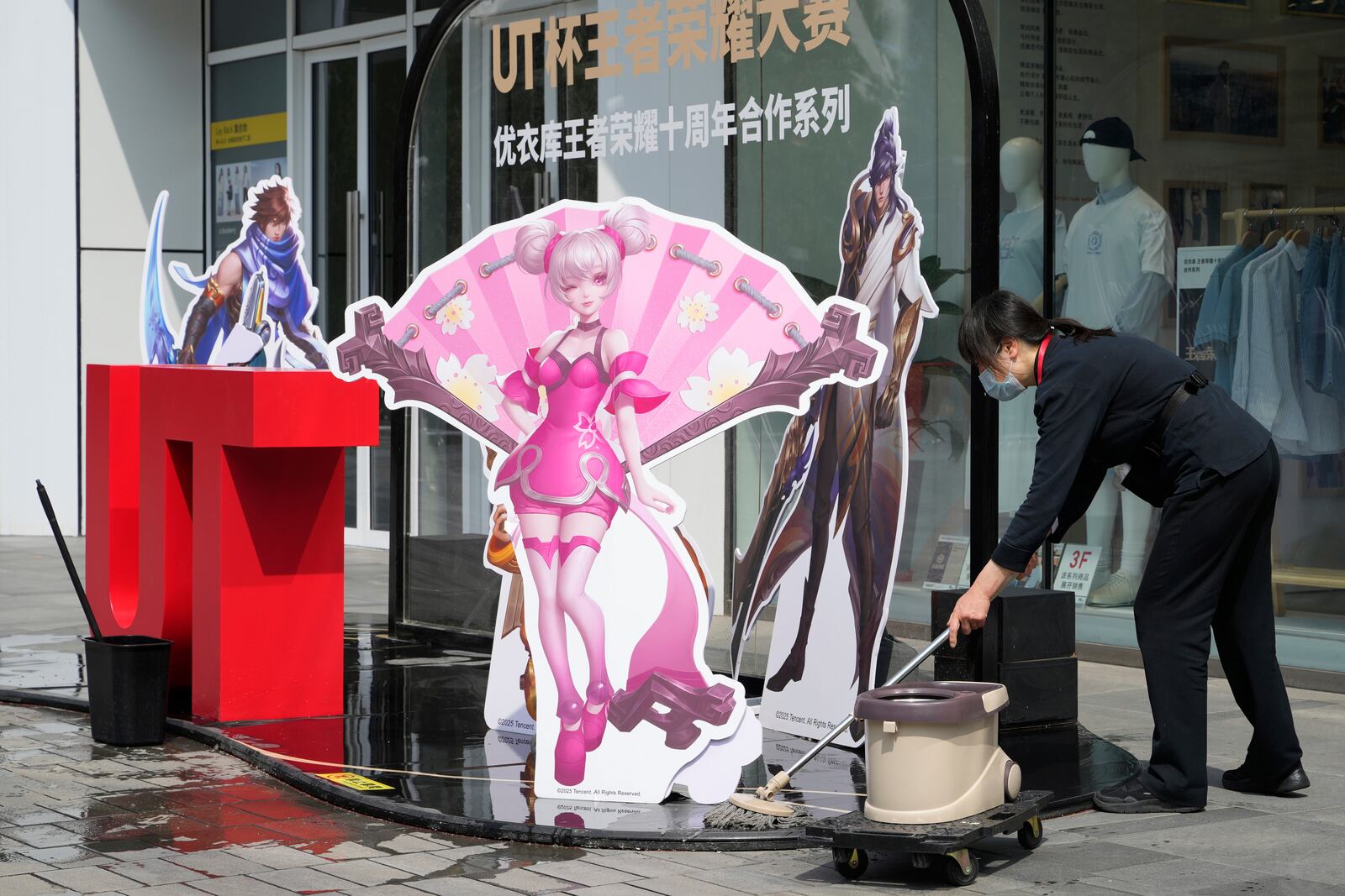A worker wipes the ground near a promotion display at a mall in Beijing, Wednesday, May 7, 2025. (AP Photo/Ng Han Guan)