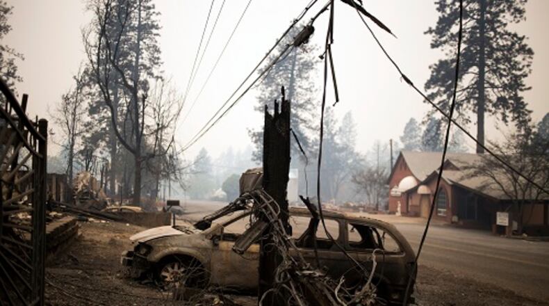 Burnt wreckage remains on Tuesday, Nov. 13, 2018, across the street from structures left unscathed by the Camp Fire in Paradise, Calif. Search teams were heading back into the devastated town on Tuesday with the grim expectation of finding more bodies in the charred remnants of the Sierra Nevada retirement community. (Jenna Schoenefeld/The New York Times)