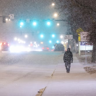 A man (right) walks as vehicles drive on West Main Street in Troy on Saturday, Jan. 24, 026. By 10 a.m. Sunday, the Miami Valley region was experiencing around 12 inches of snow in some areas. Visit DaytonDailyNews.com for the latest snow coverage. BRYANT BILLING/STAFFRYANT BILLING/STAFF