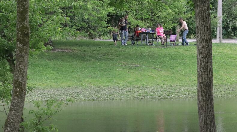 Clark County Health Commissioner is encouraging residents to maintain social distancing standards as they observe the Memorial Day weekend with activities like this family having a picnic along Buck Creek in Snyder Park Friday. BILL LACKEY/STAFF