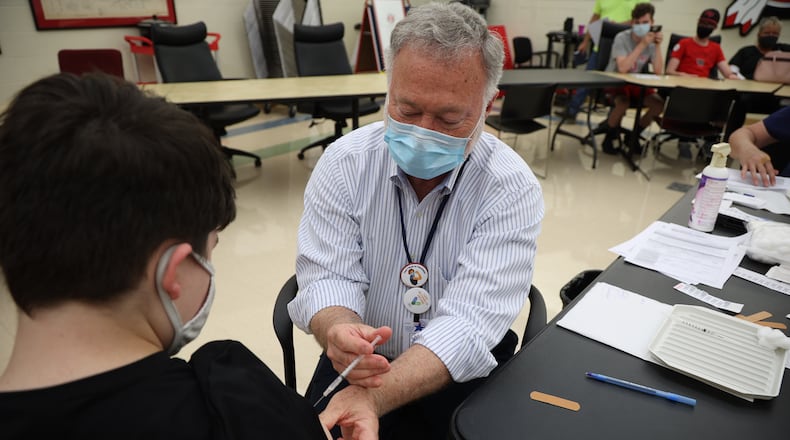 Dr. John Dobson gives Carsen Williams, 13, his COVID vaccination Wednesday during the COVID clinic at Tecumseh High School. BILL LACKEY/STAFF
