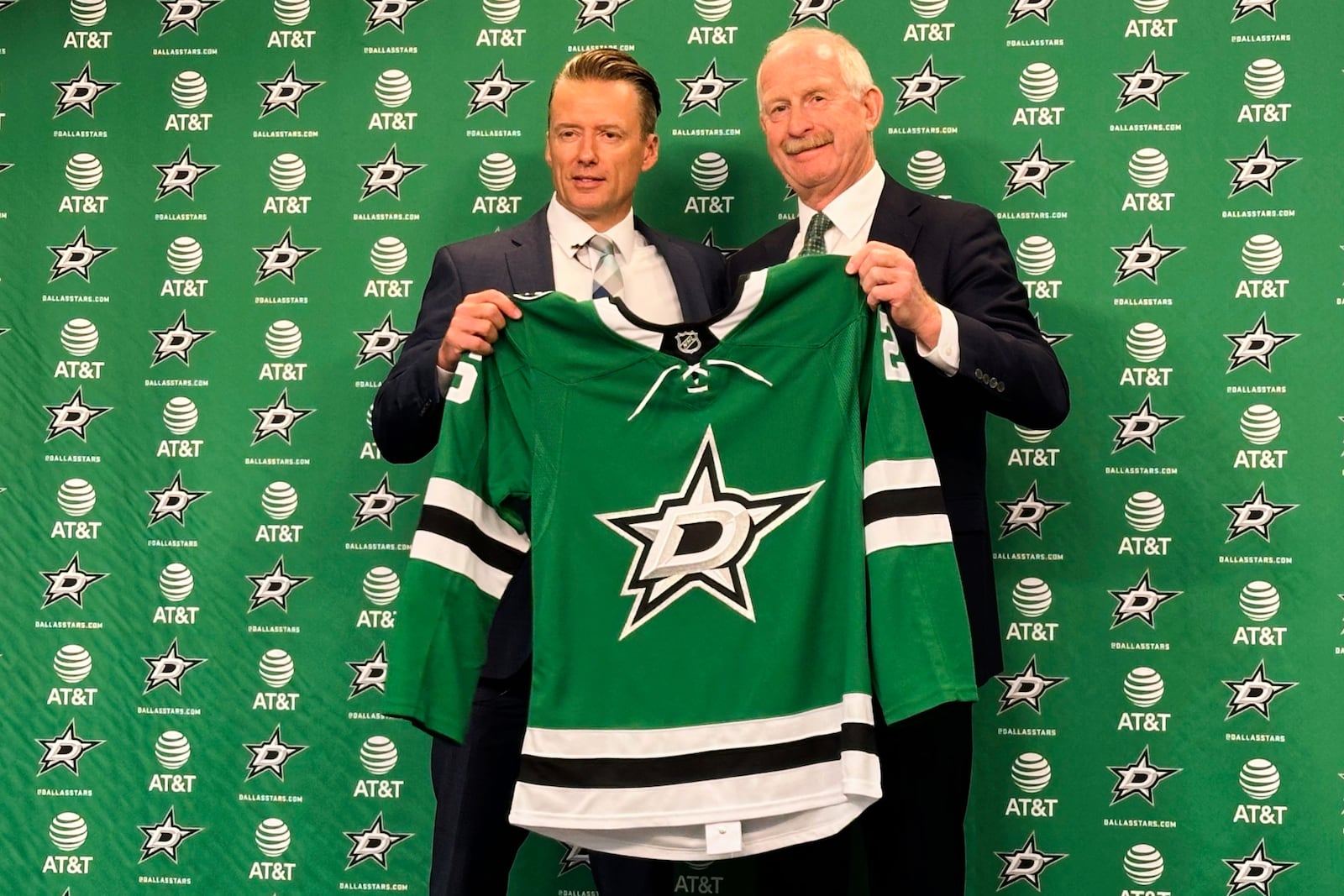 Dallas Stars new head coach Glen Gulutzan, left, and general manager Jim Nill hold up a team jersey after Gulutzan was introduced during an NHL hockey news conference, Wednesday, July 2, 2025, at the American Airlines Center in Dallas. (AP Photo/Stephen Hawkins)