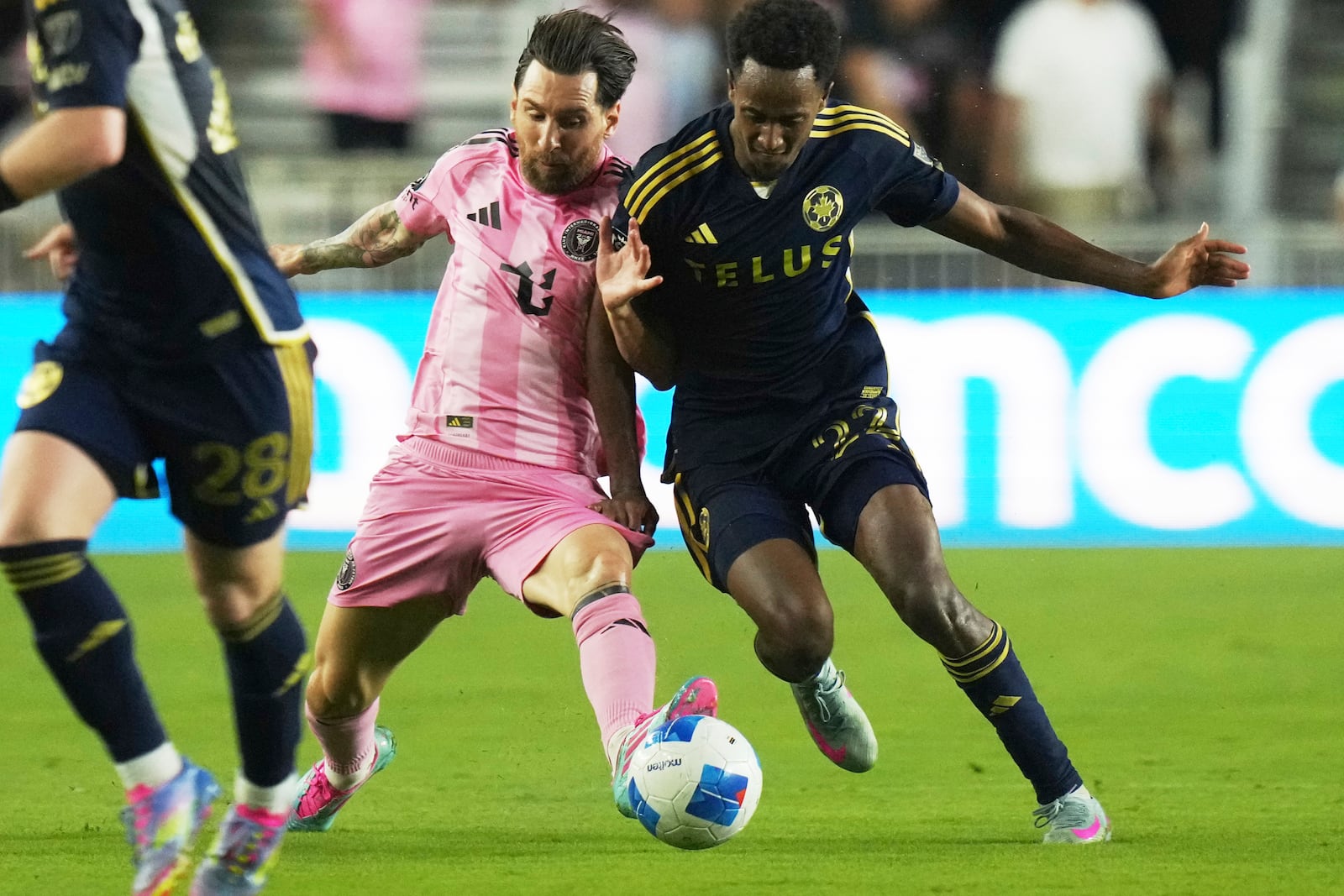 Inter Miami forward Lionel Messi, left, runs with the ball against Vancouver Whitecaps forward Ali Ahmed, right, during the first half of a CONCACAF Champions Cup second-leg semifinal soccer match, Wednesday, April 30, 2025, in Fort Lauderdale, Fla. (AP Photo/Lynne Sladky)