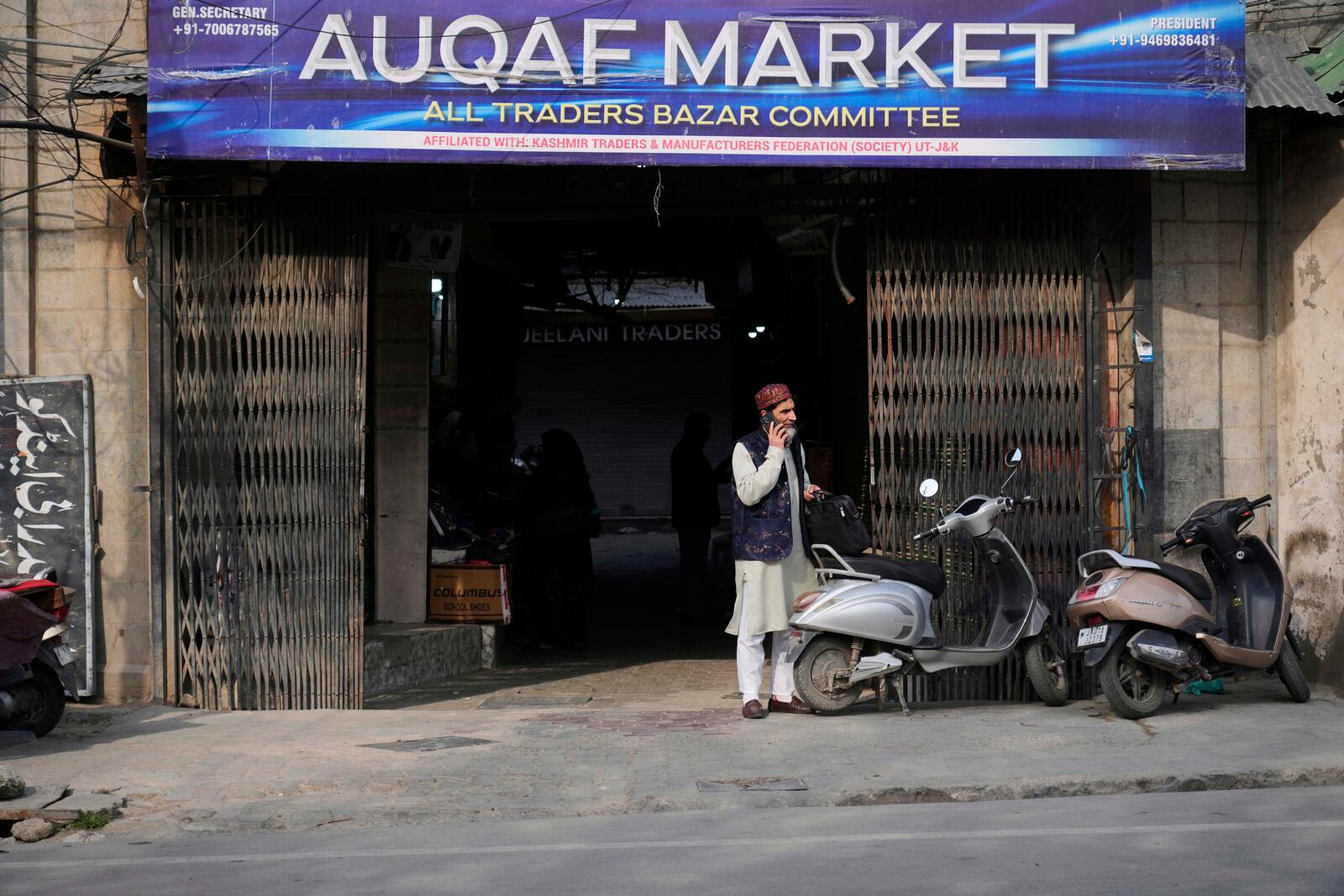 An elderly Kashmiri man talks on his cell phone outside the Auqaf Market in Srinagar, Indian controlled Kashmir, Wednesday, April 2, 2025. (AP Photo/Mukhtar Khan)