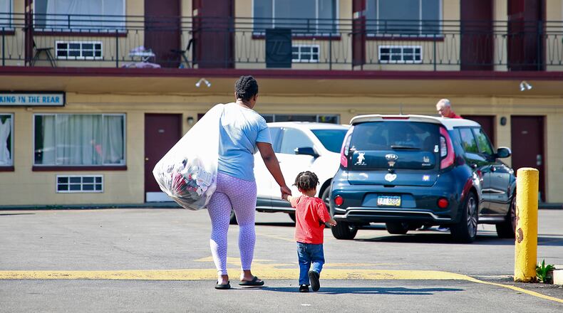 Toni Carter-White and her son carry their belongings as they leave the Executive Inn homeless shelter in Springfield on Tuesday, August 6, 2024. City Council voted the day before to reject a funding plan for the shelter. BILL LACKEY/STAFF