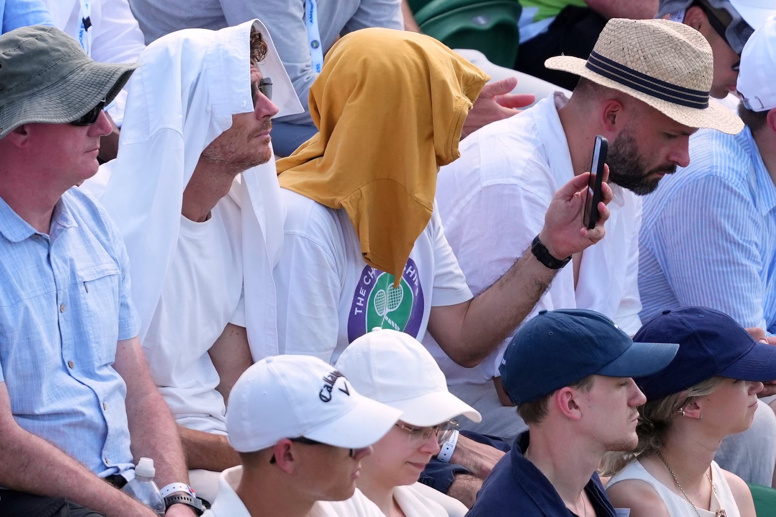 People use towels to protect their head from the sun as they watch a tennis match at the Wimbledon Tennis Championships in London, Monday, June 30, 2025. (AP Photo/Kirsty Wigglesworth)