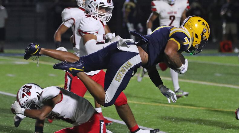 Anthony Brown dives over Wayne player for extra yards as he carries the ball during their game Friday, Sept. 9, 2022. BILL LACKEY/STAFF