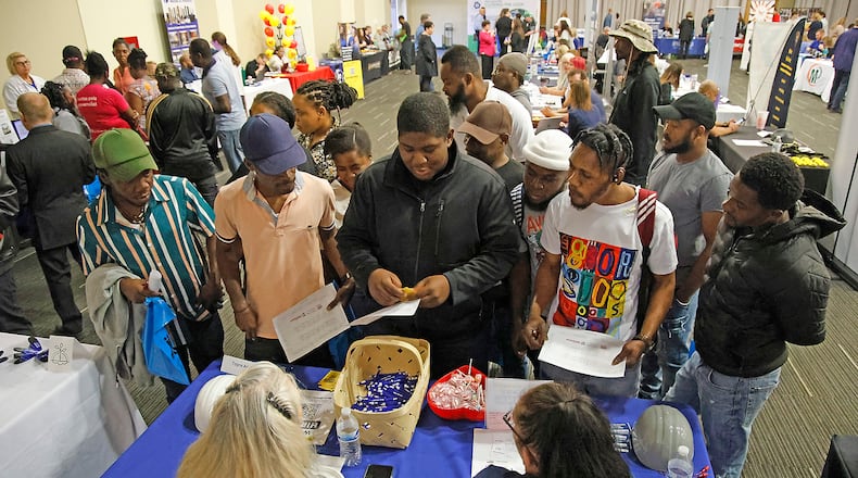 Members of Springfield's Haitian community gather around Bradley Jean, center, as he translates for them at the Topre America booth during the 14th Annual Clark County Job Fair Wednesday, April 17, 2024. The job fair featured 60 employers looking for skilled and unskilled workers. BILL LACKEY/STAFF