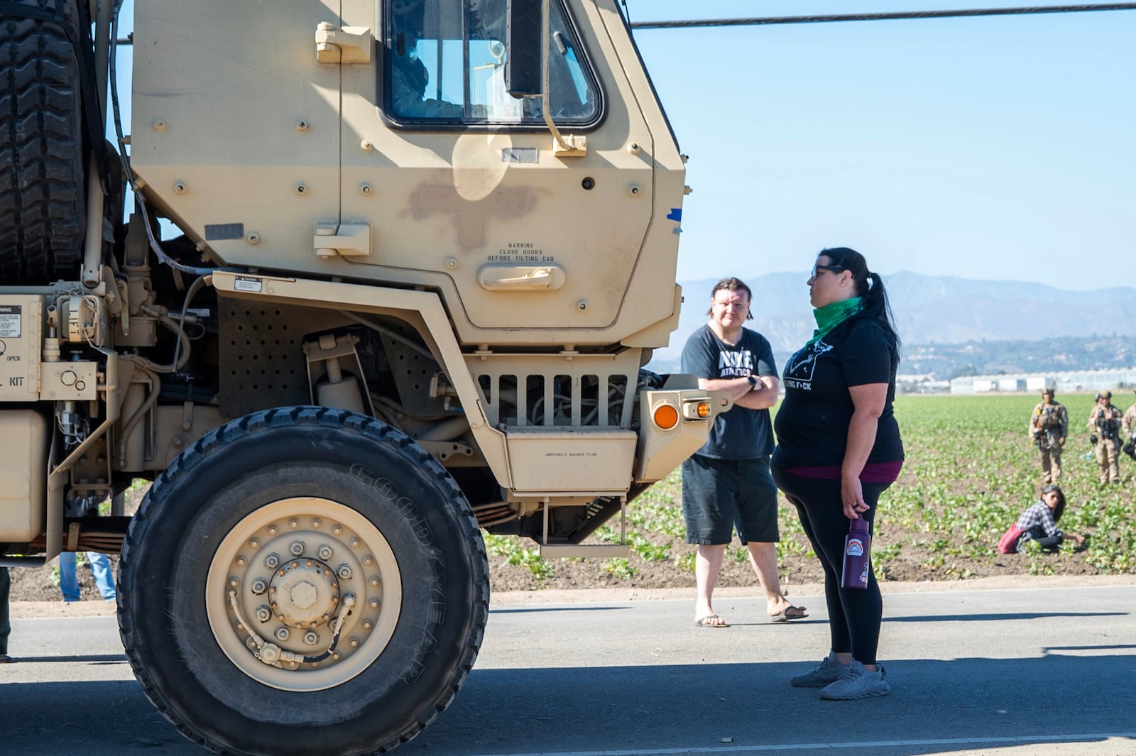 Rebecca Torres stands in front of a military vehicle approaching a federal immigration agents raid in the agriculture area of Camarillo, Calif., Thursday, July 10, 2025. (AP Photo/Michael Owen Baker)