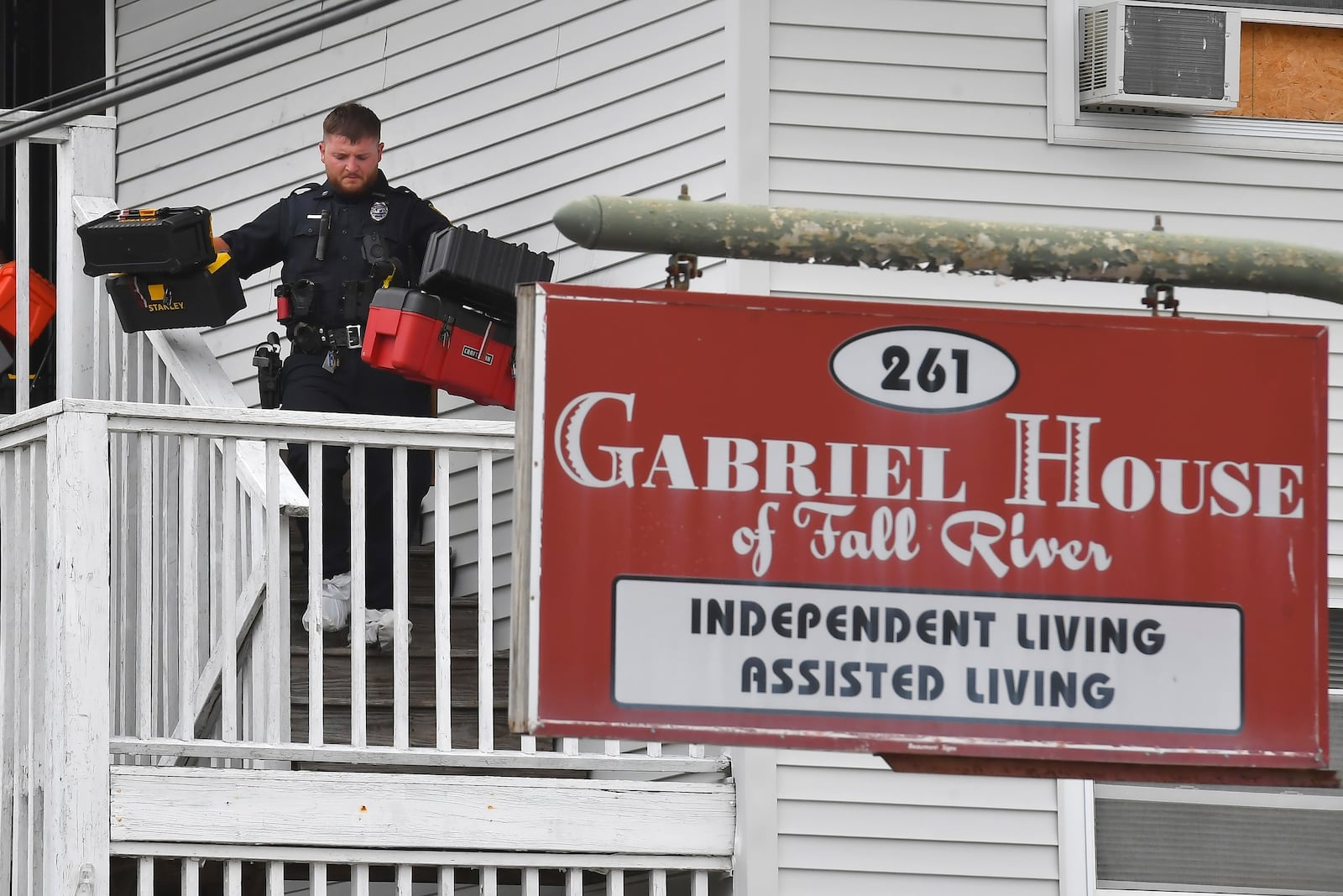 A law enforcement official removes boxes containing patient medications from the Gabriel House assisted living facility following a fire that resulted in multiple fatalities, in Fall River, Mass., Monday, July 14, 2025. (AP Photo/Steven Senne)