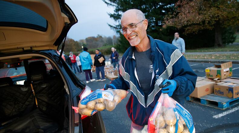 Tom Larger loads a car at the Second Harvest Food Bank food distribution at Clark State Monday, Nov. 6, 2023. BILL LACKEY/STAFF