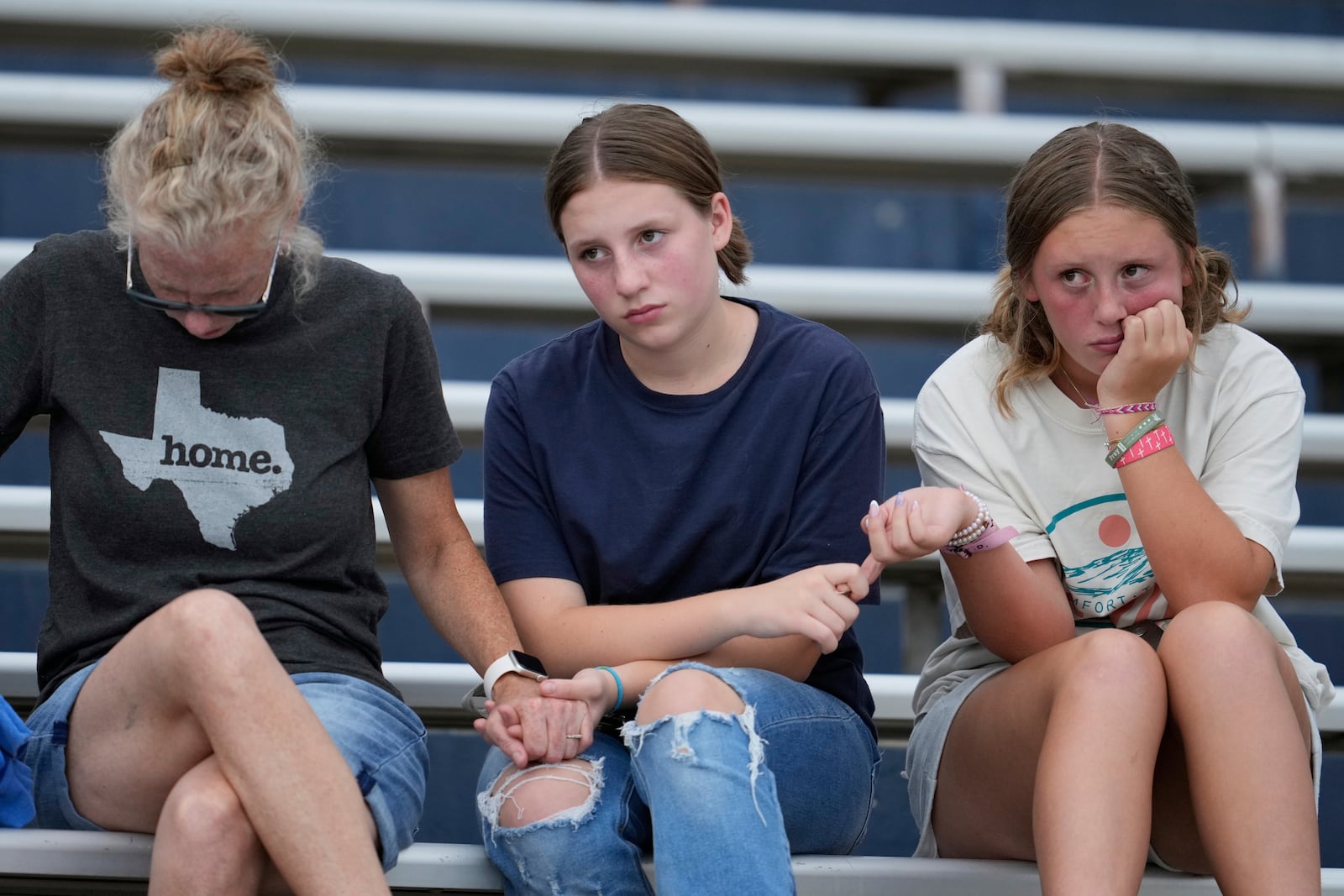 Attendees hold hands during a vigil for flooding victims at Tivy Antler Stadium on Wednesday, July 9, 2025, in Kerrville, Texas. (AP Photo/Ashley Landis)