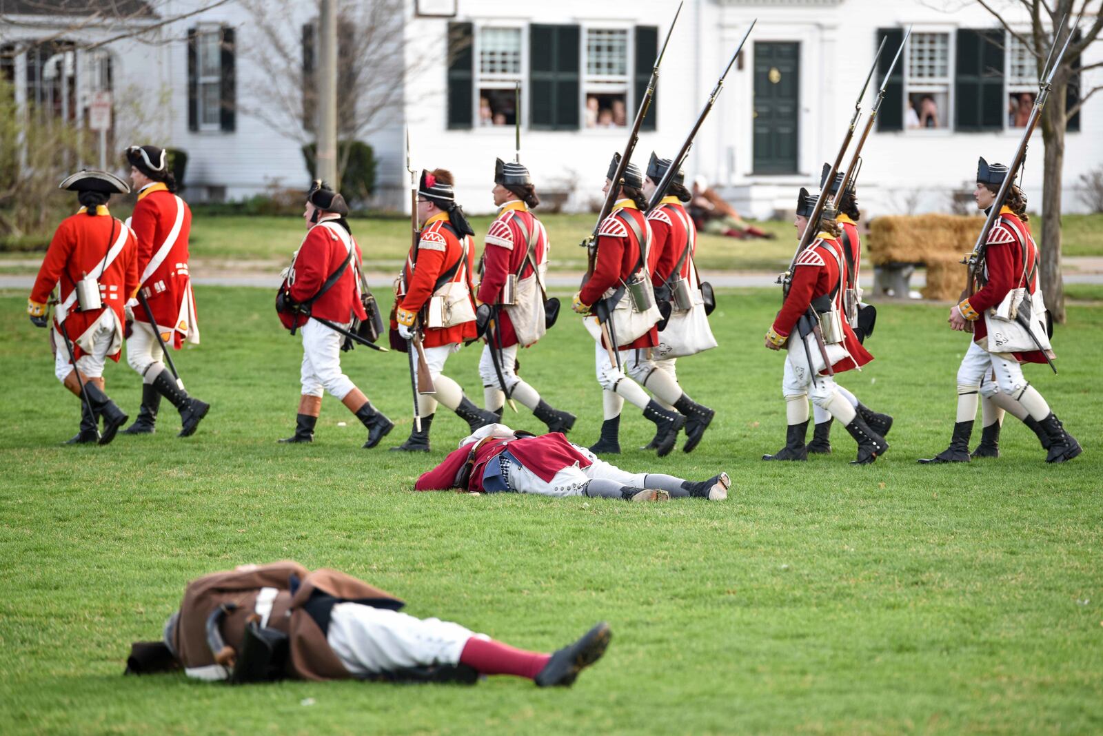 FILE - British re-enactors march past dead Colonial soldiers during the Patriots' Day re-enactment during the Patriots' Day reenactment of the battles of Lexington and Concord, on the Lexington Green in Lexington, Mass. Monday, Aril 17, 2017. (Keith Viglione/The Boston Herald via AP,FIle)