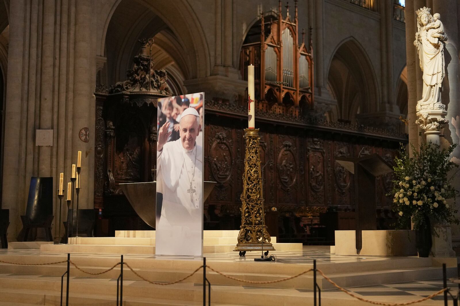 A poster showing Pope Francis has been installed inside Notre Dame cathedral, following the Vatican's announcement of his death, Monday, April 21, 2025 in Paris. (AP Photo/Thibault Camus)