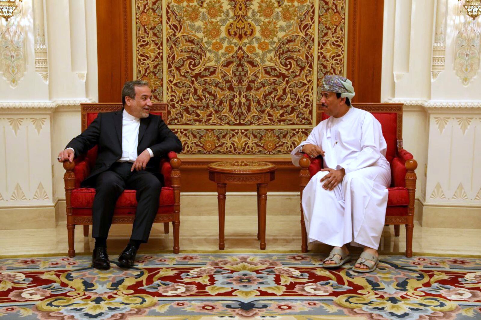 In this photo released by the Iranian Foreign Ministry, Iranian Foreign Minister Abbas Araghchi, left, speaks with an unidentified Omani official upon his arrival in Muscat, Oman, for negotiations with U.S. Mideast envoy Steve Witkoff, Sunday, May 11, 2025. (Iranian Foreign Ministry via AP)
