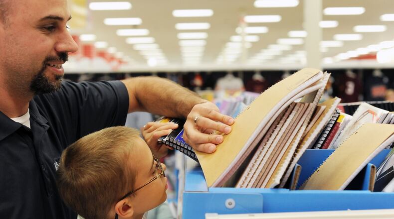 Jason Moore, left, helps his 8-year-old son Jackson Moore pick out a spiral notebook during tax-free shopping at Target on Friday, Aug. 2, 2013 in Lynchburg, Va. (AP Photo/News & Daily Advance, Sam O’Keefe)