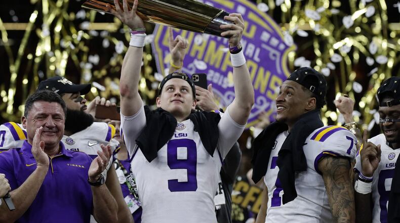 FILE - In this Monday, Jan. 13, 2020, file photo, LSU quarterback Joe Burrow holds the trophy as safety Grant Delpit looks on after LSU defeated Clemson 42-25 in the NCAA College Football Playoff national championship game, in New Orleans. Imagine if a pandemic had shortened or wiped out that last, golden season for Burrow, who won the Heisman Trophy and led LSU to the national championship. Would he still have emerged as the first overall NFL draft pick? (AP Photo/Sue Ogrocki, File)