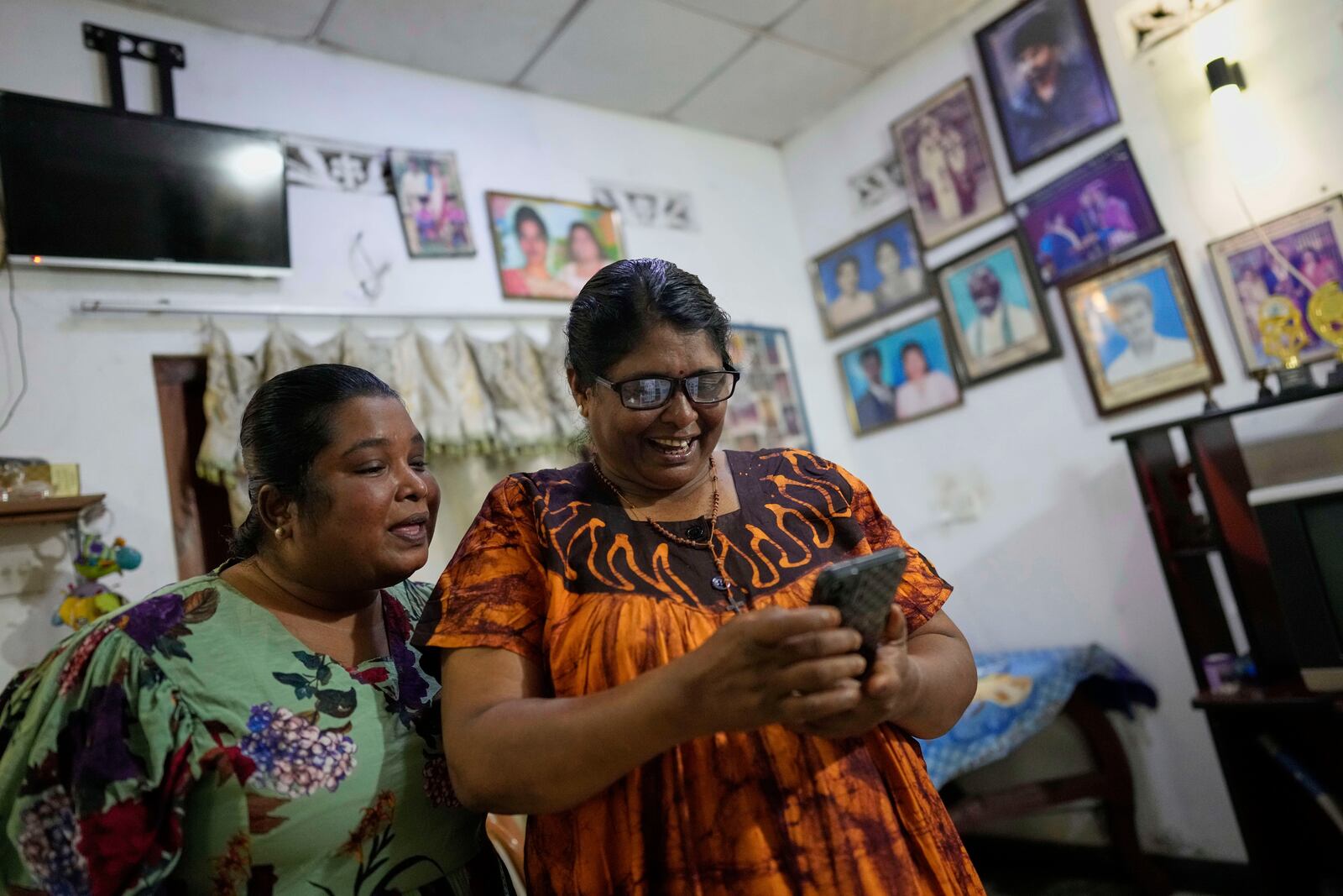 Thavaraththinam Tharsini, left, joins her mother Thavarathnam Pushparani who is on a video call with her granddaughter at their home in Paranthan, Sri Lanka, Wednesday, April 2, 2025. (AP Photo/Eranga Jayawardena)