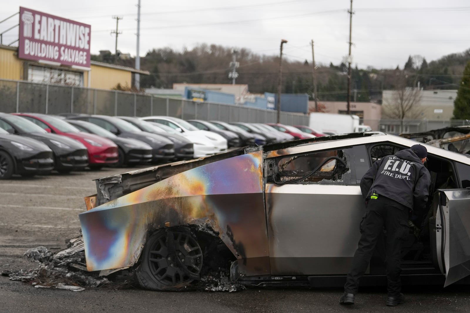 FILE - A member of the Seattle Fire Department inspects a burned Tesla Cybertruck at a Tesla lot in Seattle on March 10, 2025. (AP Photo/Lindsey Wasson, File)